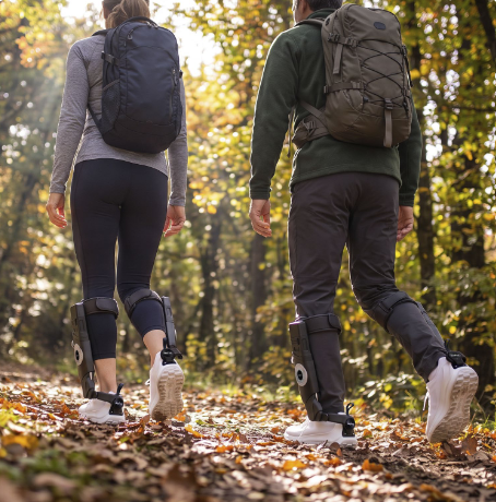 Two people walking away along a leaf-covered forest trail